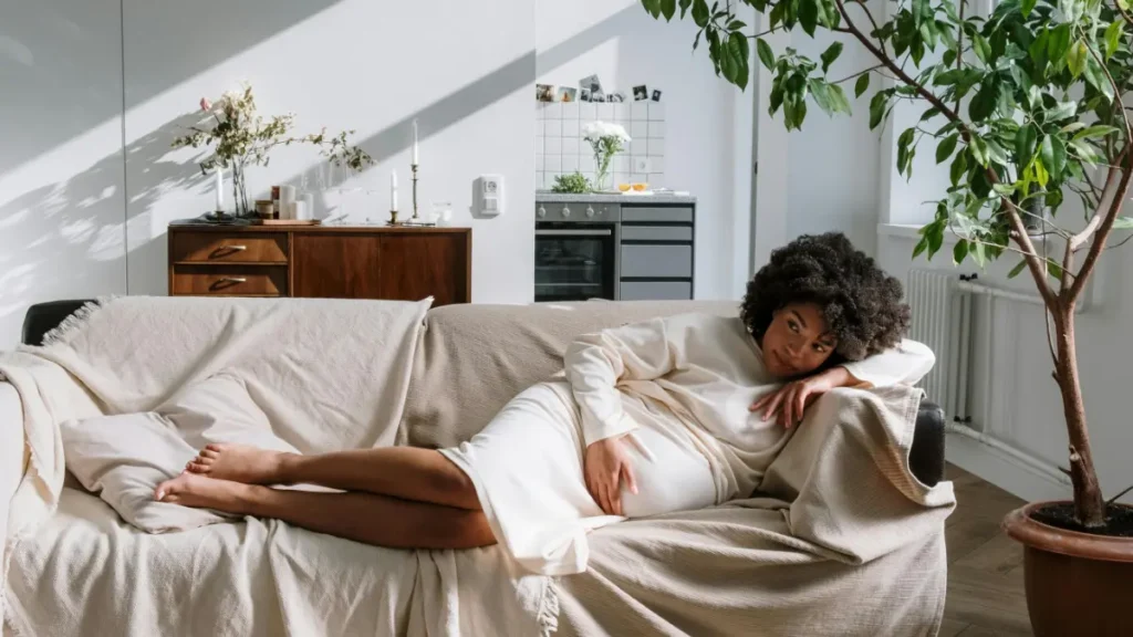 Pregnant woman laying down on a sofa considering getting life insurance